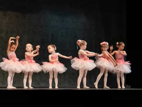 a group of girls in dresses on a stage