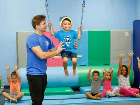 a person and a boy on a rope with children in the back