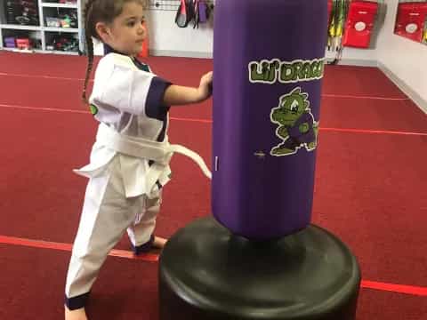a child standing next to a large blue cylinder