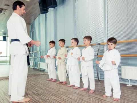 a man standing in front of a group of kids in karate uniforms