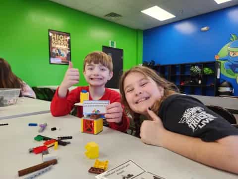 a couple of boys sitting at a table with toys and a toy