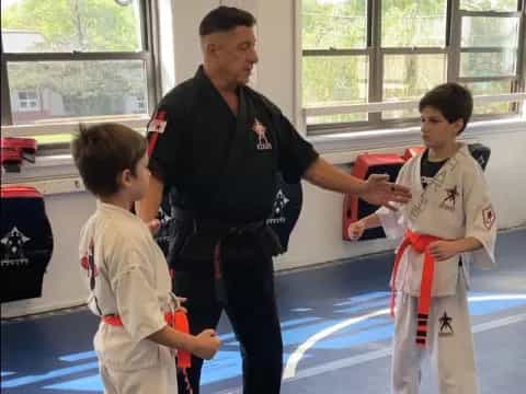 a person and two boys in karate uniforms