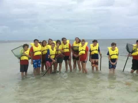 a group of people in life jackets standing in water