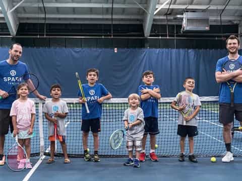 a group of kids holding tennis rackets