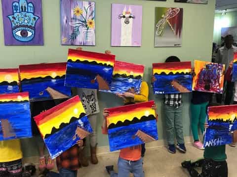 a group of kids in a room with art on the walls