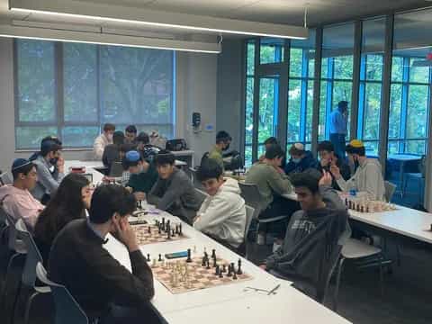 a group of people sitting around a table playing chess