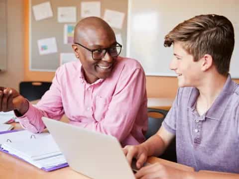 a person and a boy looking at a laptop