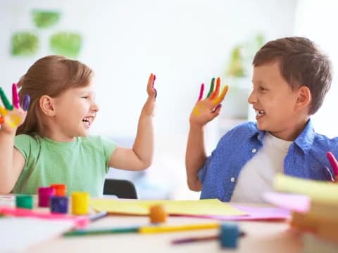 a couple of kids sitting at a table with pencils and paper