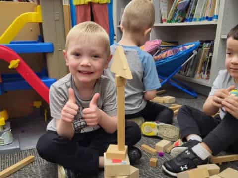 a group of children sitting on the floor holding wooden sticks