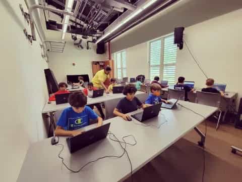 a group of people sitting at tables with laptops