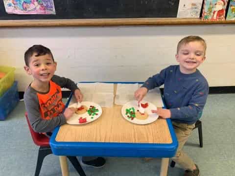 two boys sitting at a table with food on it