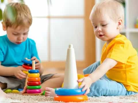 a couple of young boys playing with toys on the floor