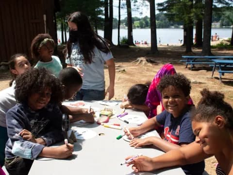 a group of children sitting at a table outside