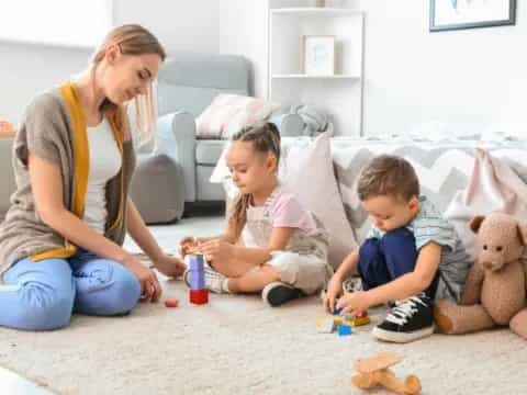 a person and two children playing with toys on the floor