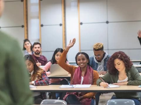 a group of people sitting at desks with their hands up