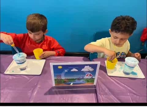 a couple of boys sitting at a table with a game on it
