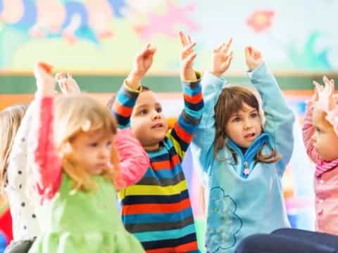 a group of children raising their hands