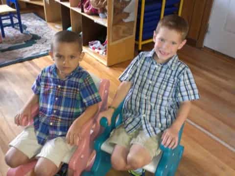 a couple of boys sitting on a blue chair in a room