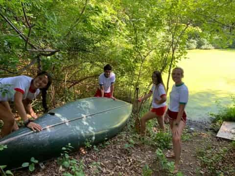 a group of people standing around a boat on a river bank