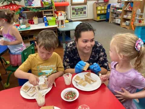 a person and two children sitting at a table with food