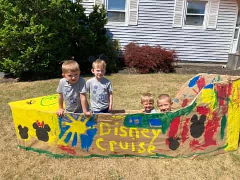a group of kids sitting on a sign in front of a house