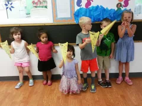 a group of children holding a yellow object in a classroom