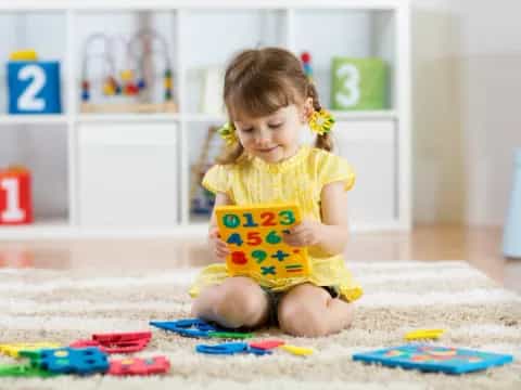 a girl sitting on the floor reading a book