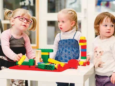 a group of children sitting at a table with toys
