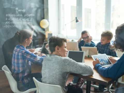 a group of people sitting at a table with laptops