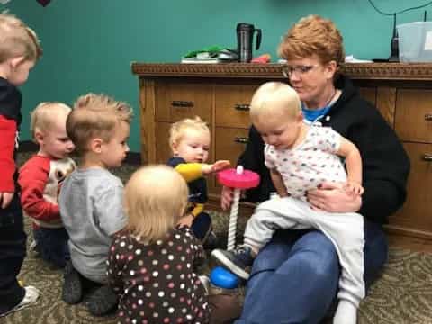 a person sitting in a chair with children around the