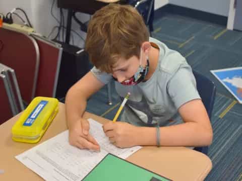 a young boy writing on a piece of paper