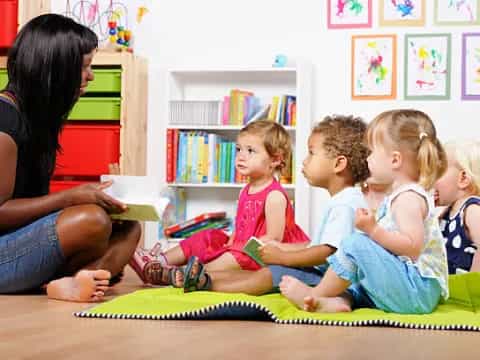 a woman reading a book to a group of children