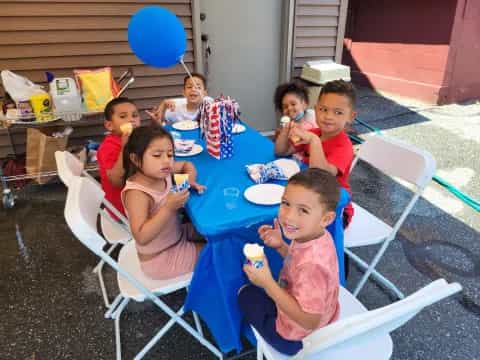 a group of children sitting at a table eating food