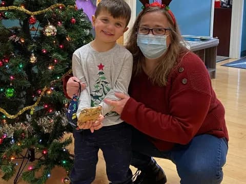a person and a boy posing for a picture next to a christmas tree