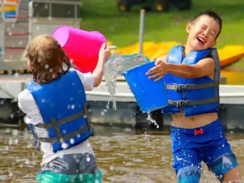 a couple of kids in life jackets in the water