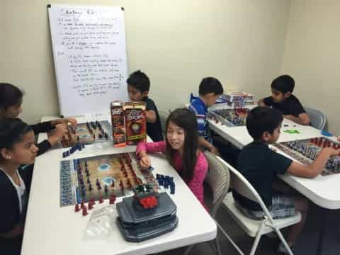 a group of children sitting around a table playing a board game